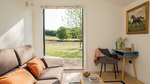 A living room with a sofa, a small table, a desk, and a painting.