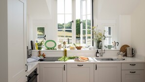 A kitchen with a window, sink, and cabinets.