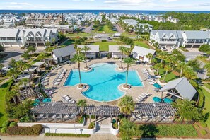 A resort with a central swimming pool, lounge areas, and a view of the ocean.