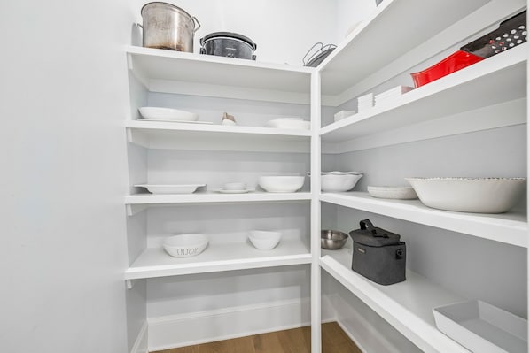 Un interior blanco con varias estanterías que contienen diferentes utensilios de cocina.
