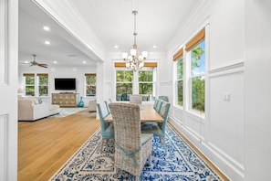 A spacious dining area with a central table, surrounded by chairs, and a patterned rug.