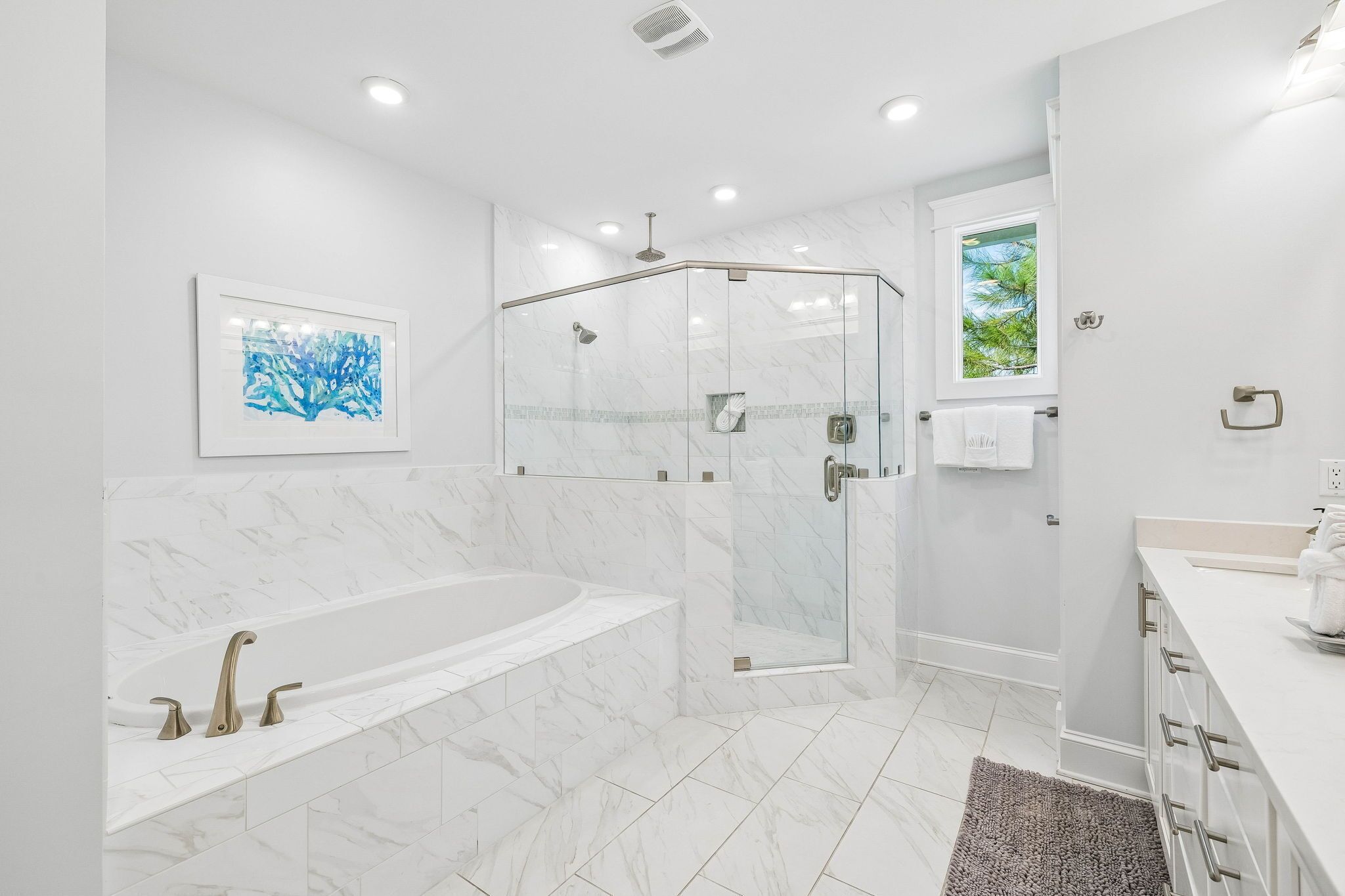 Une salle de bain moderne dotée d’une douche à parois de verre, d’une baignoire sur pieds et d’une grande fenêtre laissant entrer la lumière naturelle.