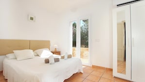 A bedroom with a bed, a nightstand, a lamp, and a sliding glass door to an outdoor area.