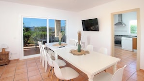 A dining area with a white table, chairs, and a view of the outdoors.