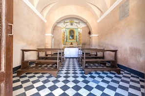 A church interior with pews, a checkered floor, and an altar with a religious icon. - Villa 'Dimora Sella - Alice' with Shared Pool, Wi-Fi, and Air Conditioning (Alghero)