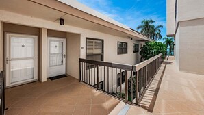 A residential building with a covered entrance, a balcony with a railing, and a clear sky. - Waterfront 2BR condo with pool, hot tub, gym, and balcony views. (St. Petersburg)