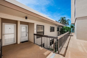 A residential building with a covered entrance, a balcony with a railing, and a clear sky. - Waterfront 2BR condo with pool, hot tub, gym, and balcony views. (St. Petersburg)