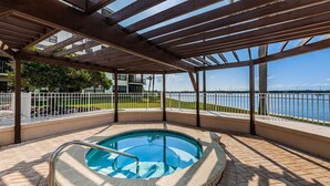 A covered outdoor swimming pool with a view of a body of water and a building in the background. - Waterfront 2BR condo with pool, hot tub, gym, and balcony views. (St. Petersburg)