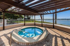 A covered outdoor swimming pool with a view of a body of water and a building in the background. - Waterfront 2BR condo with pool, hot tub, gym, and balcony views. (St. Petersburg)