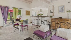 A spacious living area with a high ceiling, a dining table with chairs, a sofa, and a kitchen area in the background. - Colorful family home with garden for 6 (Longeville-sur-Mer)