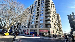 Un immeuble à plusieurs étages doté d’une architecture moderne, avec une entrée imposante, une façade en verre et une signalétique indiquant les locaux du service des ventes et du marketing.