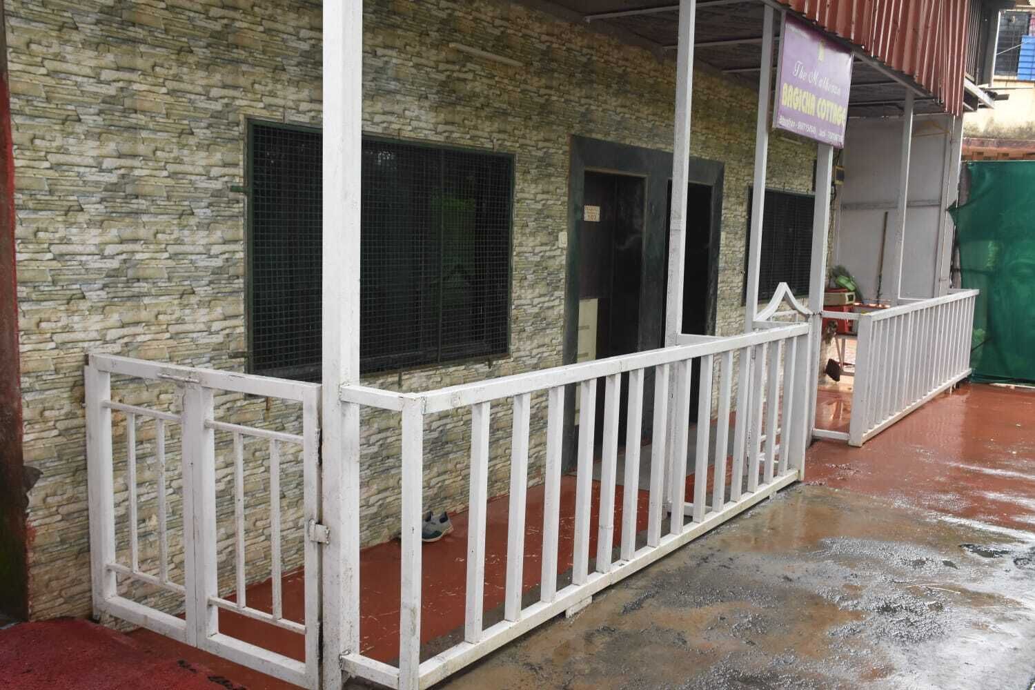 A stone building with a white railing, a sign for 'BARGAIN COTTING', and a green tarp on the ground.
