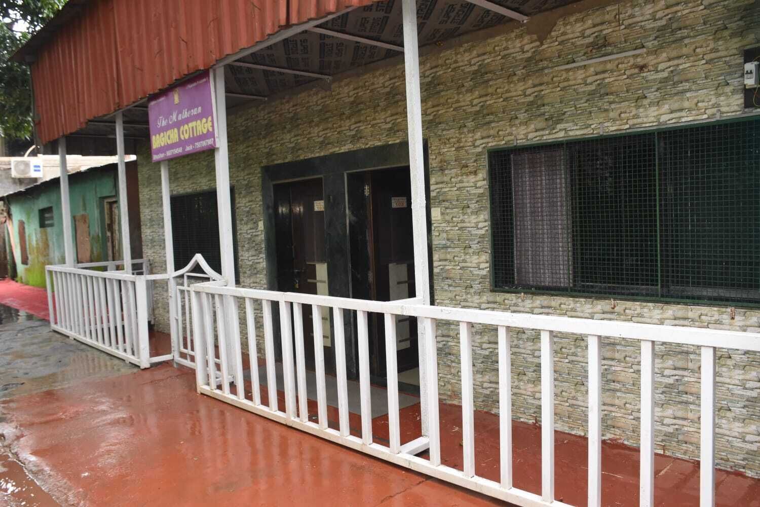 A building with a stone facade, a white railing, and a purple sign.