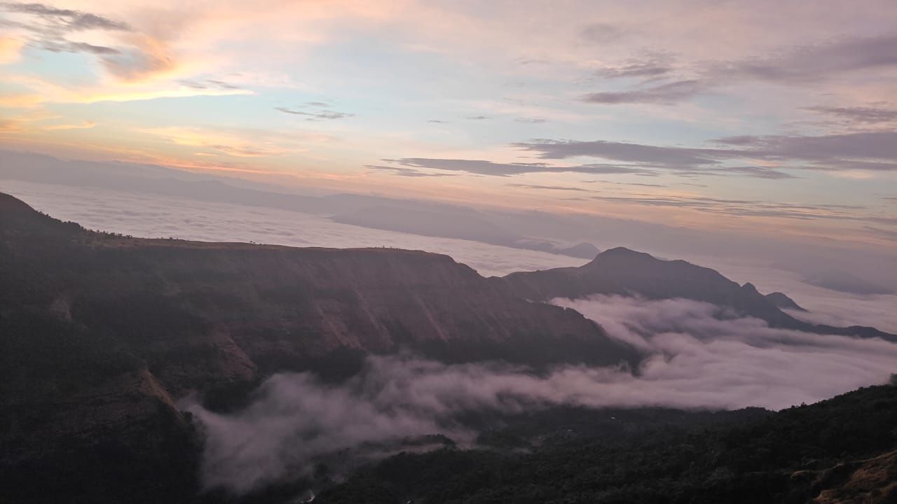 Un paysage montagneux avec une vallée et des nuages en contrebas.