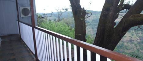 Een balkon met een witte balustrade met uitzicht op een bergachtig landschap.