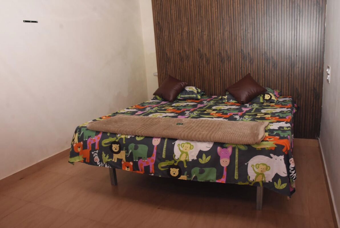 A bed with a colorful animal print bedspread, two brown pillows, and a beige throw blanket.