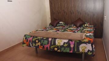 A bed with a colorful animal print bedspread, two brown pillows, and a beige throw blanket.