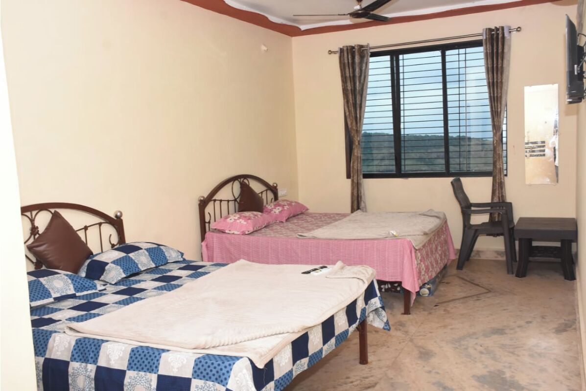 A bedroom with two beds, a window with curtains, a ceiling fan, and a small table.