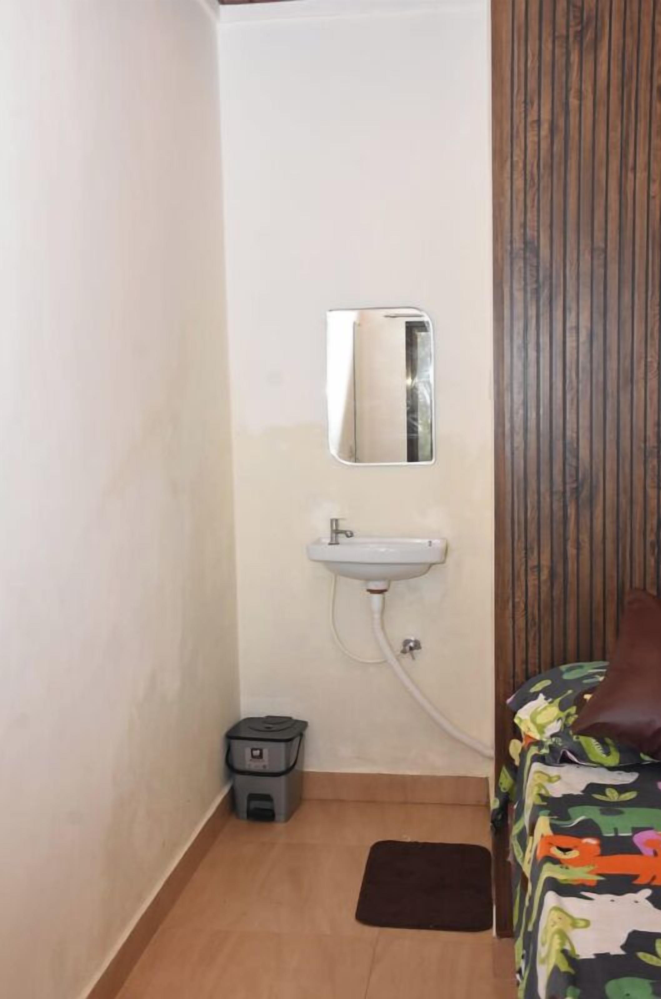 A small bathroom with a sink, mirror, and a trash bin.