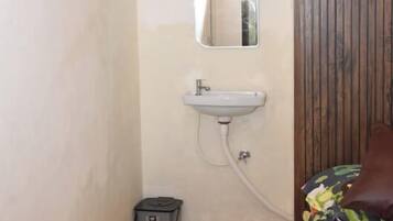 A small bathroom with a sink, mirror, and a trash bin.