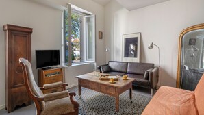 A living room with a wooden cabinet, a television, a sofa, a coffee table, and a patterned rug. - Village house for 4 people, 500m from the sea (La Bernerie-en-Retz)