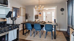 Une cuisine moderne avec un îlot central, des chaises bleues, un lustre et une cuisinière.