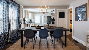 Un espace de salle à manger moderne, avec une table en bois foncé, six chaises et un lustre.