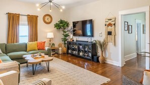 A modern living room with a green sofa, a coffee table, a TV, and a decorative plant.