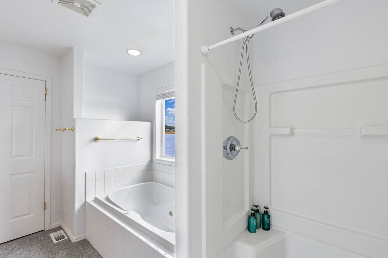 A bathroom with a bathtub, a shower, and a window providing a view.