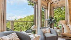 A cozy balcony with grey upholstered chairs, a globe, and a tripod-mounted camera.
