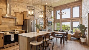 A spacious kitchen with wooden cabinetry, a large island with bar stools, and a stone accent wall.