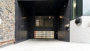A modern building entrance with a stone facade, a black metal door, and a window with horizontal blinds. - Curated 2B/2B DT Halifax (Halifax)