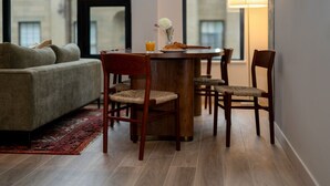 A cozy living room with a sofa, wooden chairs, a dining table, and a lamp. - Curated 2B/2B DT Halifax (Halifax)