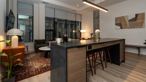 A modern kitchen with a central island, bar stools, and a coffee machine.