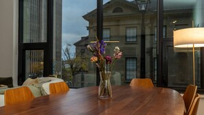 A dining area with a wooden table, chairs, and a vase of flowers.