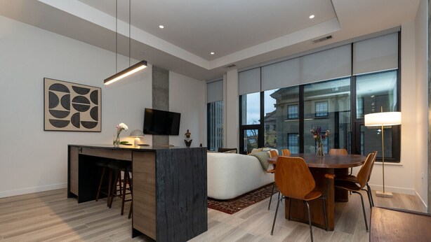 A modern living room with a sofa, dining table, and bar area.