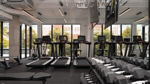 A gym with treadmills, stationary bikes, and dumbbells.