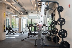 Une salle de sport équipée de divers appareils d’entraînement, notamment des tapis de course, des appareils de musculation et des poids libres.
