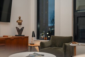 A modern living room with a green armchair, a wooden side table, a black lamp, and a sculpture on a wooden cabinet. - *NEW Executive Mid-Century Modern 2B/2B (Halifax)