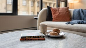 A cozy room with a round table, a plate with two doughnuts, and a stack of books. - *NEW Designer Mid-Century Modern 2B/2B (Halifax)