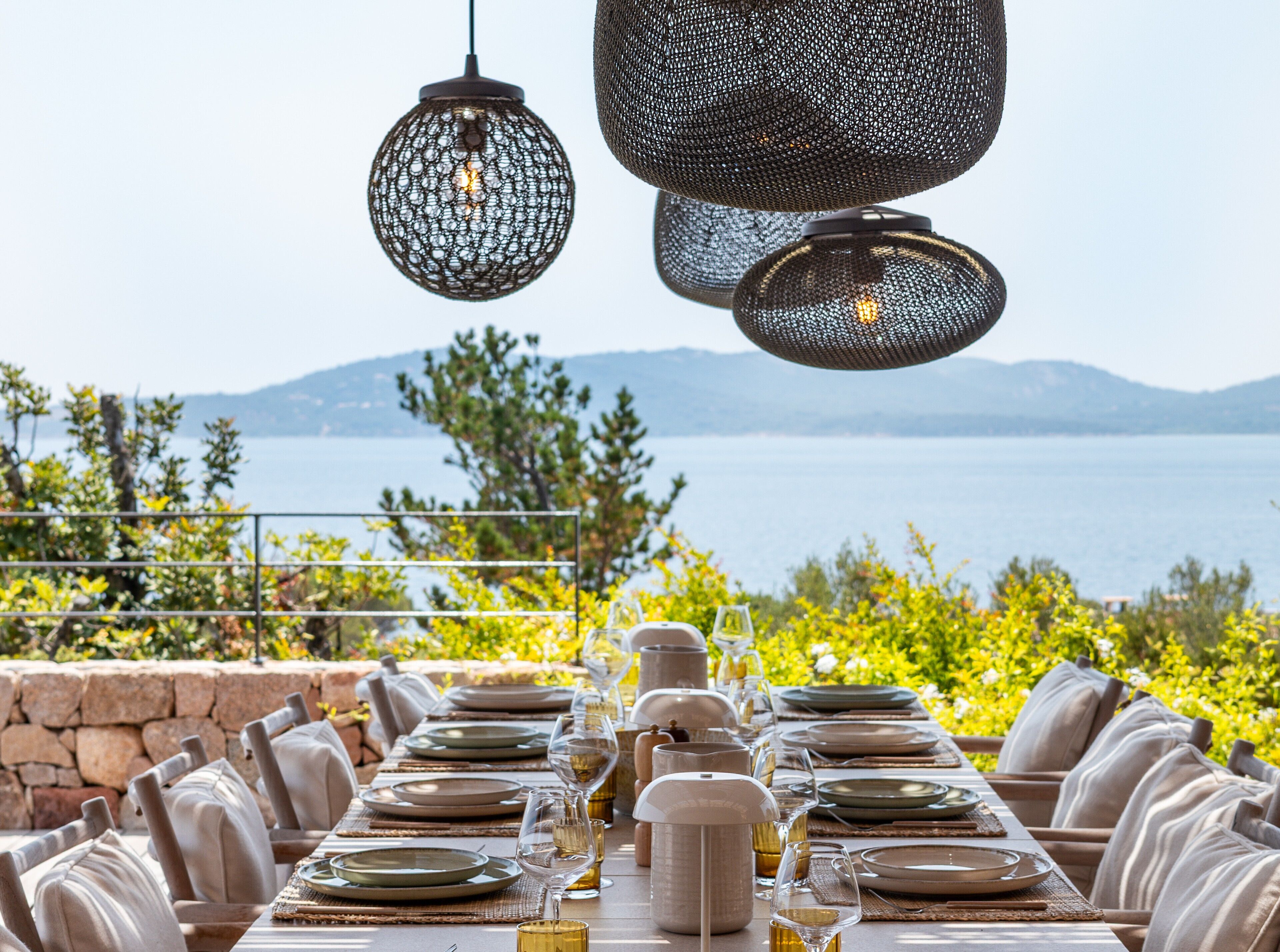 A table set for dining with a view of the sea and mountains.