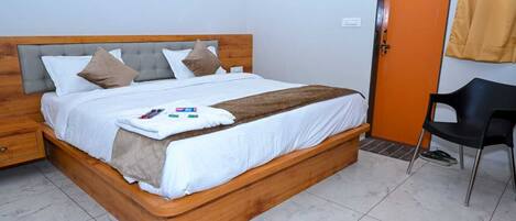 A single bed with a wooden headboard, white bedding, and a brown throw blanket.