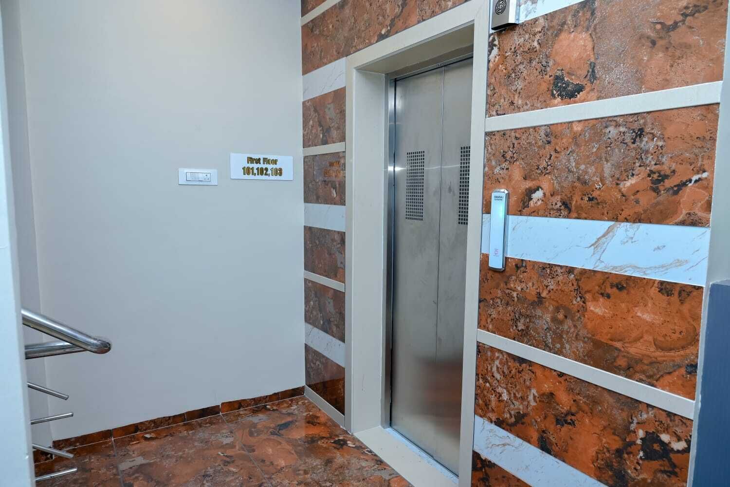 A hotel elevator with a marble wall and a sign indicating the first floor.