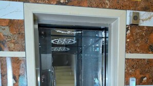 An elevator with a glass door, a keypad, and a patterned floor. - Shivprakash Executive  (Tuljapur)