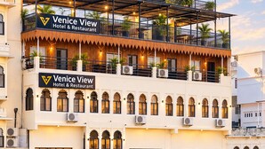 A hotel with a sign reading 'Venice View Hotel & Restaurant,' featuring a balcony with plants and a reflection in the water. - Venice View Hotel & Restaurant (Udaipur)