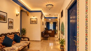 A hotel lobby with a reception desk, seating area, and a reception desk with a sign. - Venice View Hotel & Restaurant (Udaipur)