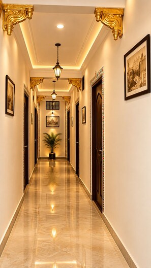A hallway with a polished marble floor, ornate gold detailing on the ceiling, and framed pictures on the walls. - Venice View Hotel & Restaurant (Udaipur)