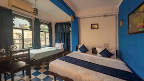 A hotel room with a checkered floor, two single beds, a desk with a chair, and a ceiling fan. - Venice View Hotel & Restaurant (Udaipur)