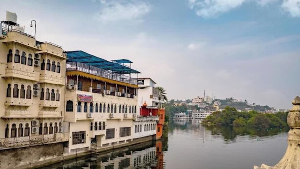 A riverside view with traditional architecture, including a building with a balcony and a covered area. - Venice View Hotel & Restaurant (Udaipur)