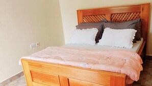 Un lit en bois avec une tête de lit, un tapis moelleux et un sol carrelé.